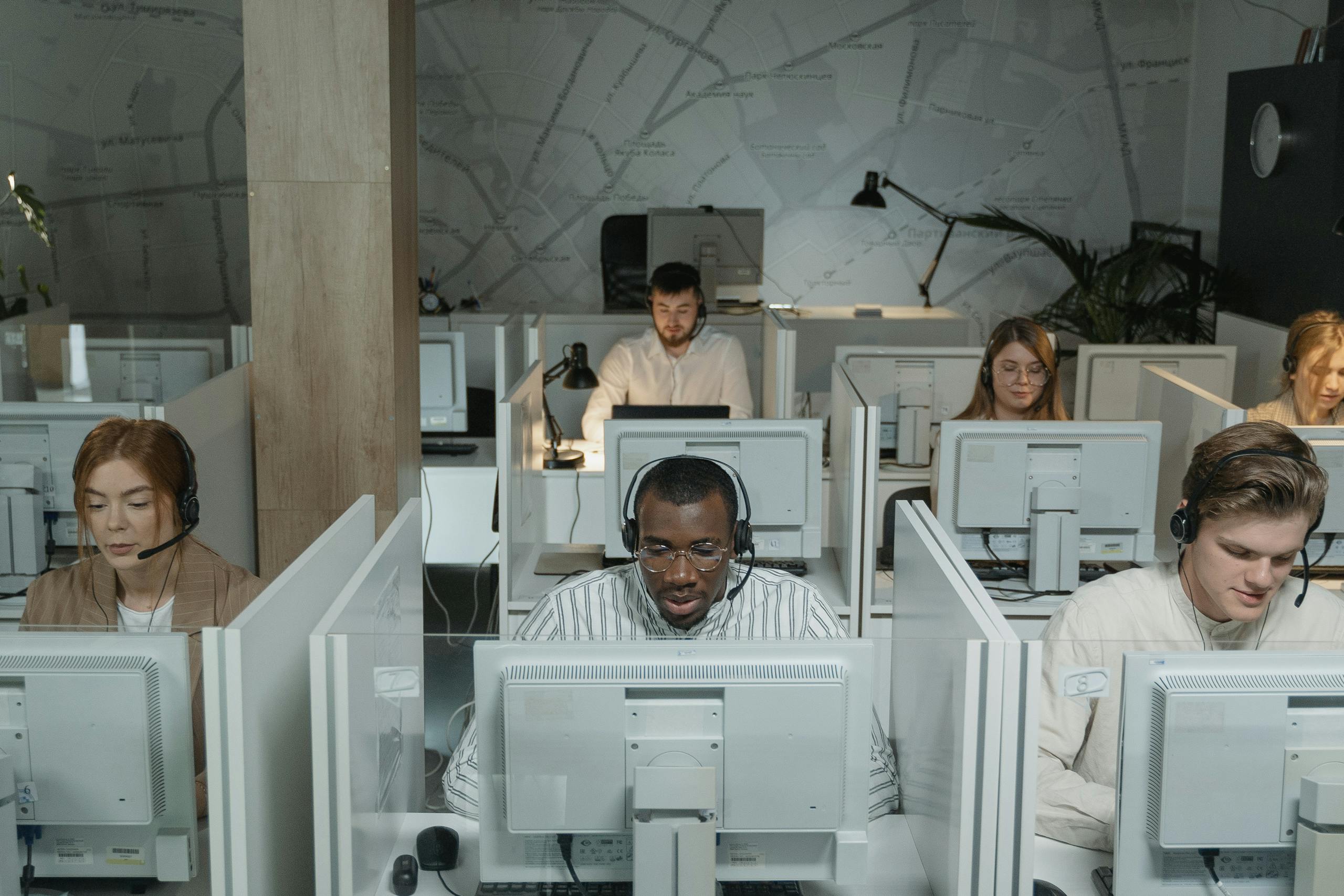 A diverse group of call center agents working in an organized office setting, focused on assisting customers.
